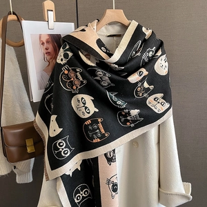 Détail d'un châle en tricot à motif de chat avec un design tricolore noir, jaune et blanc