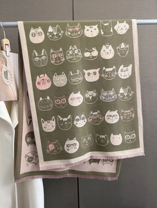 Détail d'une écharpe en tricot à motifs de chats avec des franges rose et olive