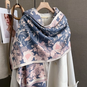 Détail des motifs jacquard fleurs et oiseaux sur une écharpe d'hiver gris-bleu