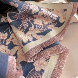 Vue détaillée du tricot jacquard floral et des franges de glands roses sur l'écharpe