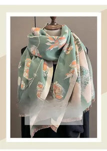 Détail d'une écharpe à fleurs avec bord à franges présentée sur un mannequin minimaliste