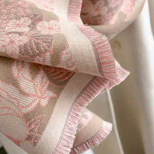 Vue macro détaillée du motif floral jacquard et des bords effilochés doux de l'écharpe d'hiver