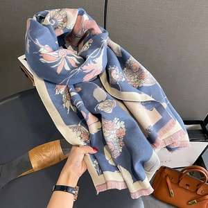 Détail d'une écharpe en maille jacquard à fleurs avec des bords à franges en bleu doux