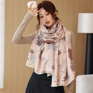 Close-up of floral cashmere feel scarf with detailed fringe on soft pink fabric