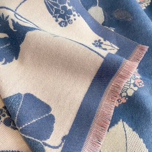 Détail du motif jacquard de feuilles et des franges roses douces sur un châle épais