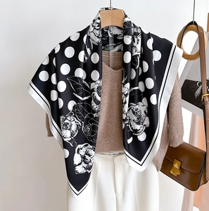 Gros plan d'un élégant foulard en soie noir avec pois blancs et motifs de roses