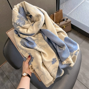 Detail of soft cream scarf with blue floral pattern and delicate fringe edges