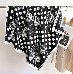 Détail d'un foulard en soie à pois et fleurs suspendu à côté d'un blazer élégant