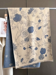Close-up of floral cashmere scarf featuring navy blue poppy patterns and hand-tied tassels