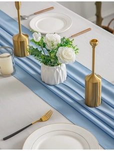 Detail of light blue chiffon table runner with elegant pleated texture on a white table