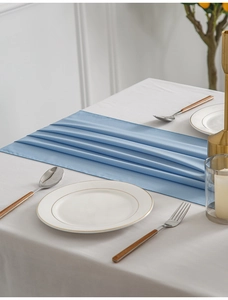 Detail of light blue wrinkled chiffon table runner on white linen with gold decor