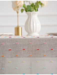 Close-up of linen tablecloth with colorful tufted polka dots and decorative tassels