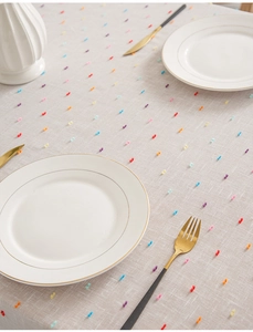 Detail of colorful tufted dots on a light beige textured tablecloth with cotton-linen fabric