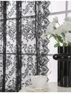 Detailed embroidery of rose patterns on black lace curtain with scalloped edges