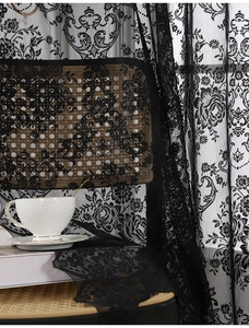 Detail of black floral lace curtain with fine embroidery on vintage rattan furniture