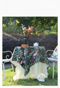 Detail of tropical floral tablecloth with flamingo print and white lace trim styling