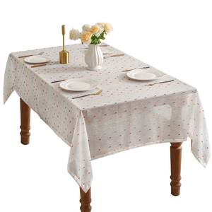 White bohemian tablecloth with colorful pom-pom tufts on a dark wood dining table