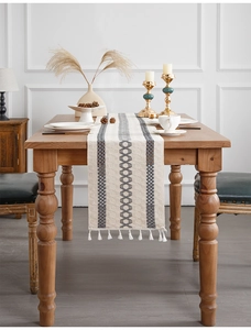 Detailed view of woven cotton table runner with grey stripes and white fringe tassels