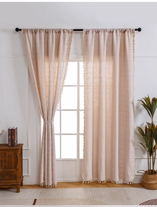 Detail of light beige plaid cotton linen curtain with decorative white fringe tassels