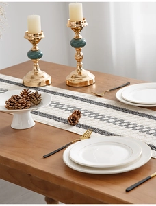 Detail of striped cotton table runner with fringe on a wooden table with dining decor