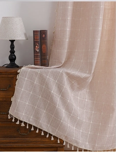 Detail of pink plaid linen curtain showing woven texture and delicate white fringe tassels