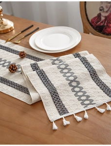 Detail of woven table runner with grey geometric patterns and white fringe tassels