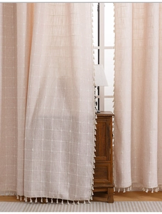Detail of bohemian cotton linen curtains with striped texture and small white tassels