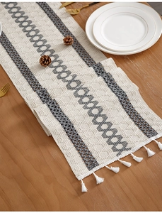 Detailed view of woven table runner with geometric patterns and delicate white tassels
