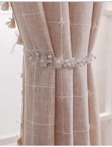 Detail of white faux pearl and floral bead curtain tieback on striped fabric