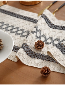 Detail of white cotton table runner with grey geometric knit pattern and hollowed edges