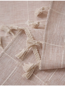 Detail of bohemian cotton linen curtain fabric with white grid patterns and tassels