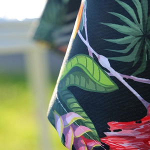 Tropical floral print tablecloth with vibrant green leaves on black twill fabric