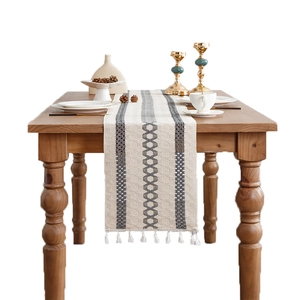 Boho cotton linen table runner with grey geometric patterns and tassels on wooden table