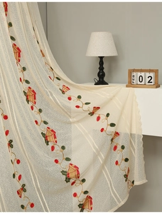 Detail of beige lace curtain with festive bell embroidery and floral berry patterns