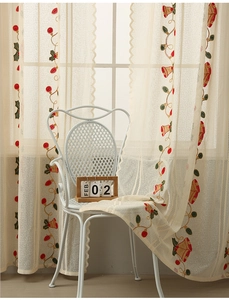 Detail of beige sheer curtain with festive red bell and holly leaf embroidery