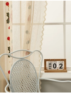 Detail of beige lace curtain with red berry embroidery and delicate scalloped edges