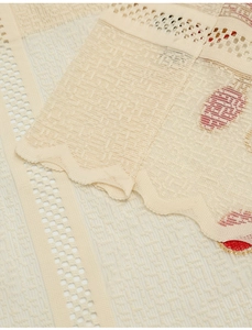 Close-up of beige sheer lace curtain with red flower embroidery and scalloped edges
