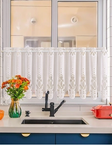 Close-up of white lace kitchen cafe curtain with embroidered hollow patterns on window