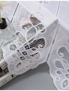 Macro shot of white lace kitchen curtain showing fine floral texture and hollow mesh