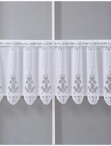 Detail of white lace cafe curtain featuring intricate floral embroidery and scalloped edges