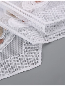 Detail of white mesh lace fabric with delicate scalloped edges and tiny brown patterns