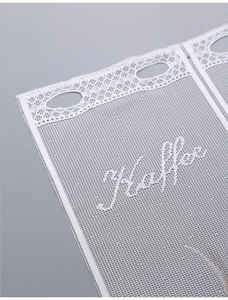 Close-up of white lace curtain with embroidered Coffee lettering and mesh texture