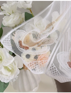 Detail of white lace kitchen curtain featuring delicate butterfly embroidery and mesh texture