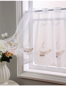 Close-up of white lace kitchen curtain with coffee cup embroidery and Kaffee text