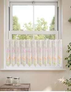 Detailed close-up of white lace curtain featuring colorful butterfly patterns and scalloped edges