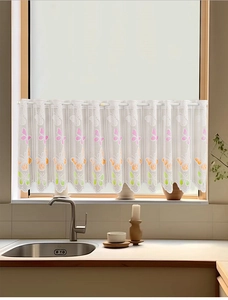Close-up of white lace curtain featuring colorful butterfly print and scalloped edges