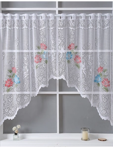 Detailed close-up of white lace curtain featuring pink and blue floral embroidery and wavy hem