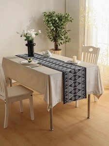 Detail of geometric table runner and solid beige tablecloth in a cozy home setting