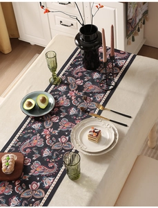 Dettaglio di un runner da tavola vintage con motivi floreali paisley su tessuto scuro