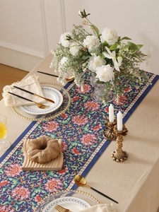 Detail of vintage floral table runner on dining table with golden cutlery and decor